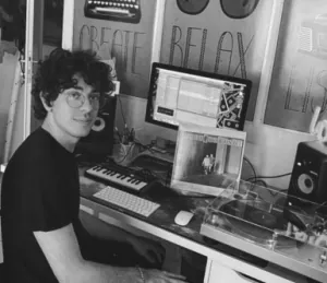 Marco Cherubini smiling at his music production desk, in black and white