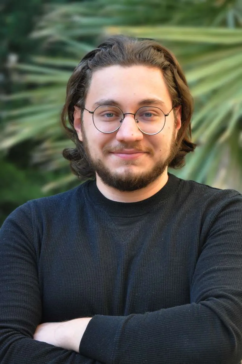 Portrait of Mouaz El Molkey, smiling, with glasses and a beard
